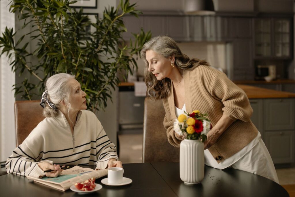Older woman and younger companion enjoying a shared activity at a table.